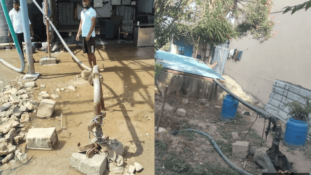 Workers inspect a damaged site with exposed piping and a blue barrel in a backyard area.