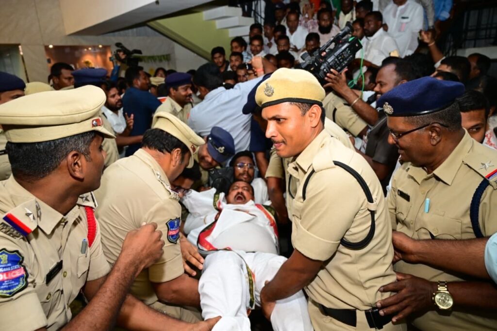 Police officers restrain a crowd at a gathering with a person being carried away.