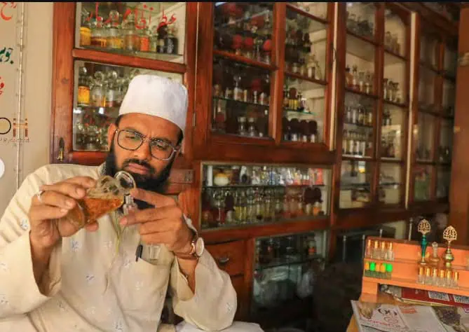 Man wearing white traditional cap aromas perfume in a shop with glass shelves of bottles in the old city.